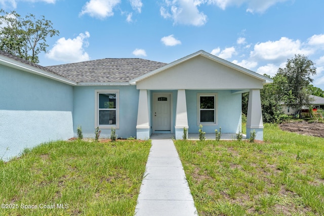 2100 Cogan Dr SE, Palm Bay, FL 32909 - view of front of property with stucco siding, a porch, a front yard, and a shingled roof