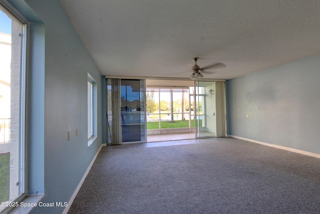 carpeted spare room with floor to ceiling windows, ceiling fan, a textured ceiling, and baseboards