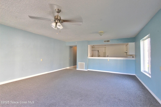 unfurnished living room featuring a ceiling fan, baseboards, visible vents, and a textured ceiling