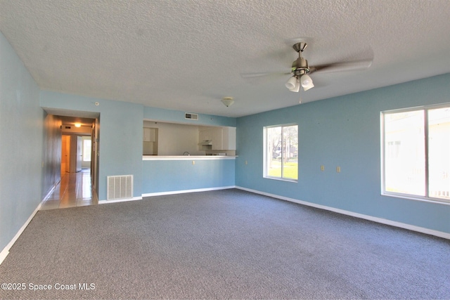 unfurnished living room with carpet floors, visible vents, baseboards, and a ceiling fan