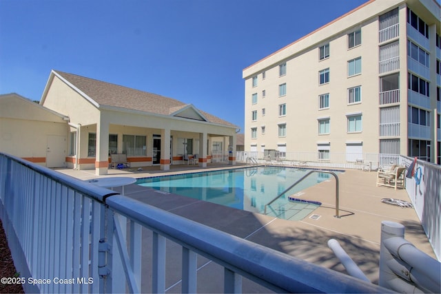 pool with a patio area and fence