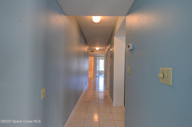 hallway featuring light tile patterned floors and baseboards