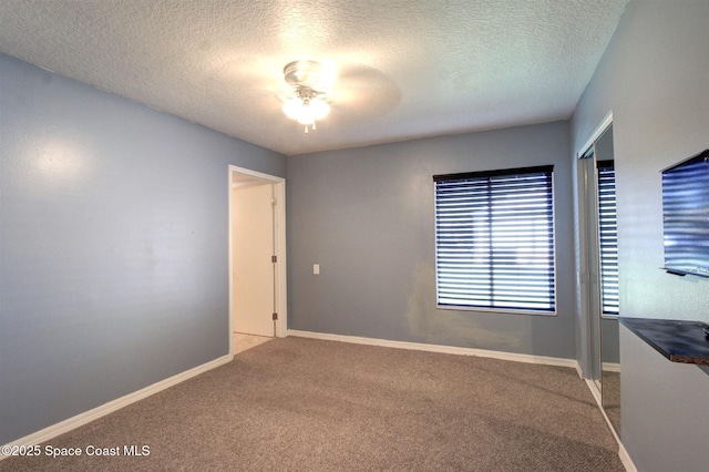 spare room featuring carpet, ceiling fan, a textured ceiling, and baseboards