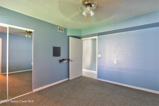 unfurnished bedroom with a textured ceiling, a closet, carpet, and visible vents