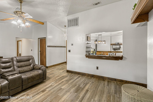 living area featuring visible vents, a textured ceiling, and wood finished floors