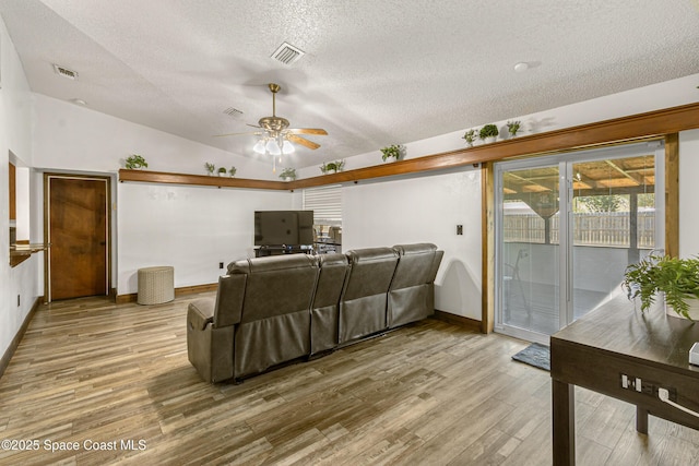 living area with lofted ceiling, visible vents, and wood finished floors