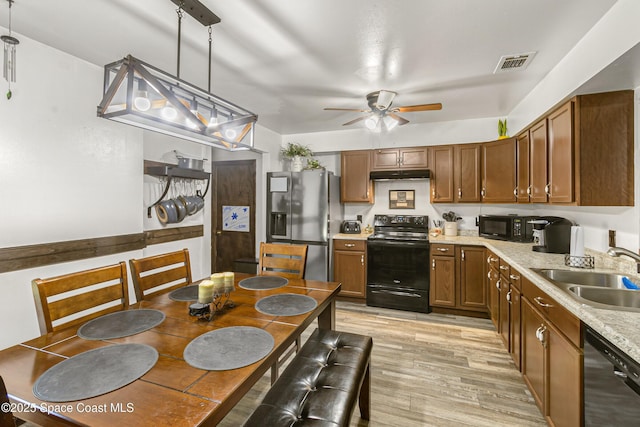 kitchen with under cabinet range hood, a sink, visible vents, light countertops, and black appliances