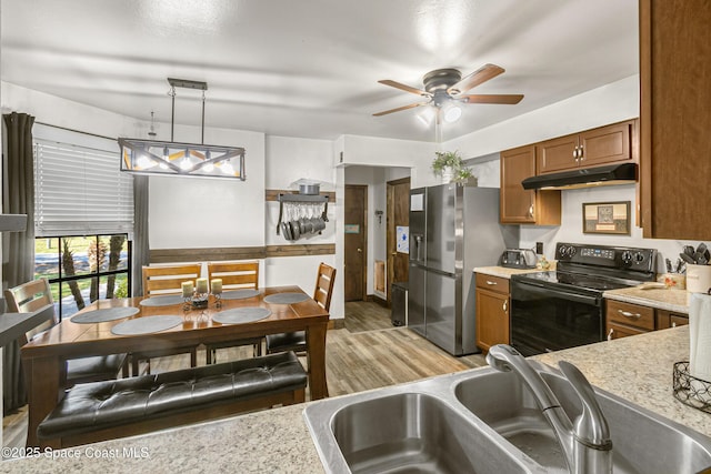 kitchen with brown cabinets, black electric range, under cabinet range hood, stainless steel refrigerator with ice dispenser, and a sink