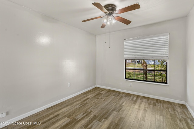 spare room featuring ceiling fan, baseboards, and wood finished floors