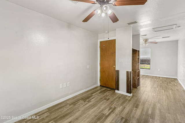 spare room featuring baseboards, attic access, visible vents, and wood finished floors