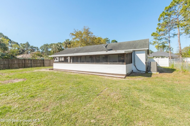 back of property featuring a yard, a fenced backyard, and a sunroom