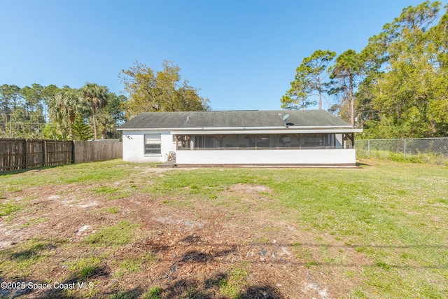 back of property with a sunroom, a fenced backyard, stucco siding, and a yard