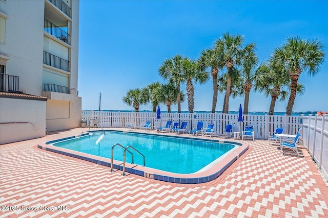 community pool with a patio area and fence