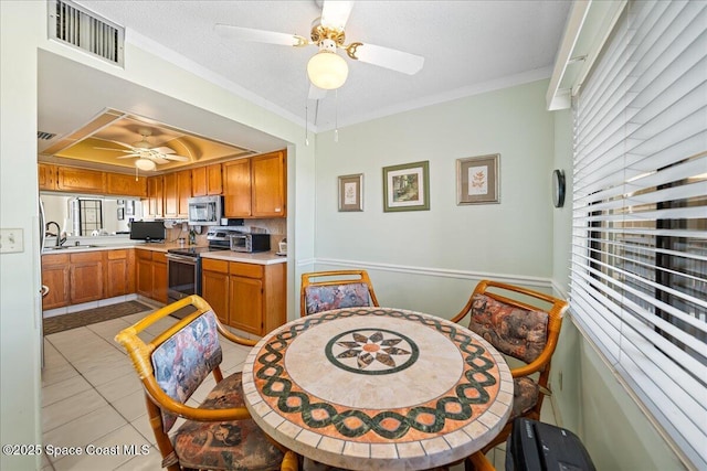 kitchen with crown molding, light tile patterned floors, light countertops, visible vents, and appliances with stainless steel finishes