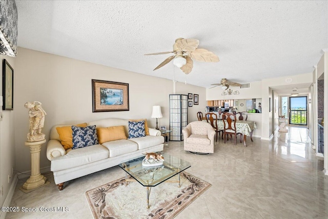 living room with baseboards, ceiling fan, visible vents, and a textured ceiling