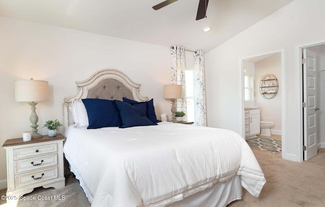 bedroom with lofted ceiling, ensuite bathroom, light carpet, ceiling fan, and baseboards