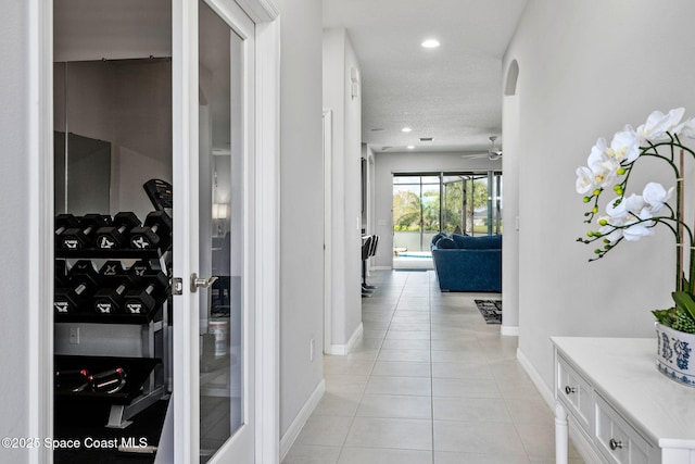 corridor featuring baseboards, light tile patterned flooring, and recessed lighting