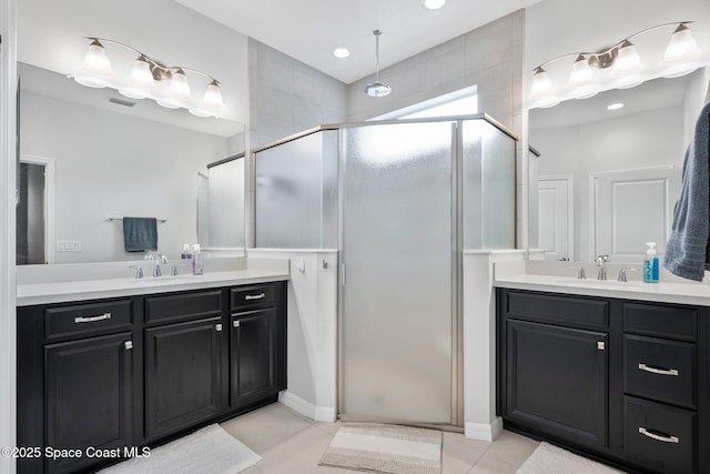 bathroom with a stall shower, two vanities, a sink, and tile patterned flooring