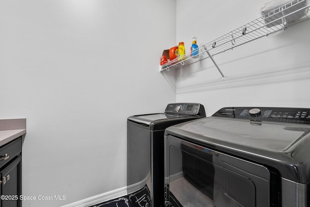 laundry room with washing machine and dryer, cabinet space, and baseboards