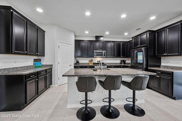 kitchen with refrigerator with ice dispenser, dark cabinetry, stainless steel microwave, and a sink