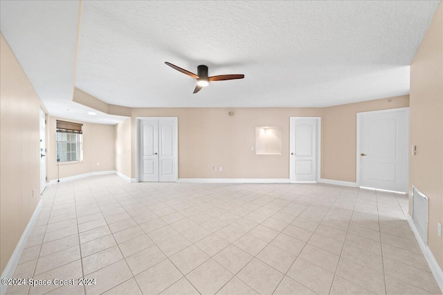 empty room featuring a textured ceiling, visible vents, a ceiling fan, and baseboards