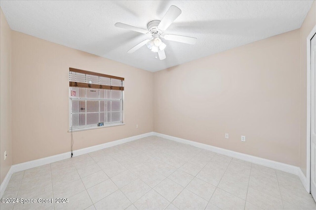 spare room featuring ceiling fan, baseboards, and a textured ceiling