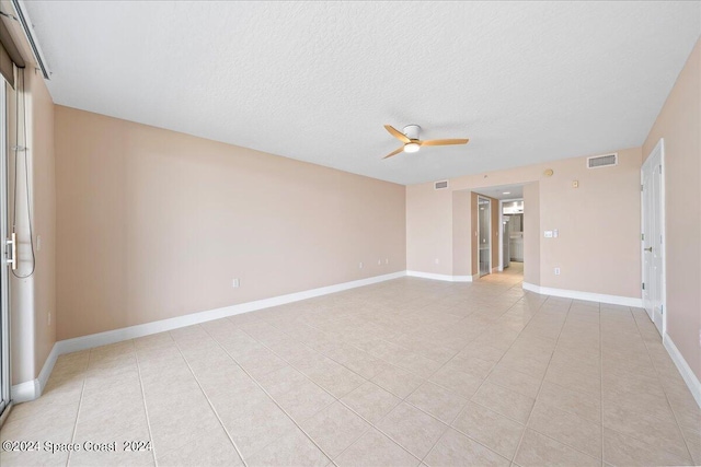 unfurnished room with ceiling fan, a textured ceiling, visible vents, and baseboards