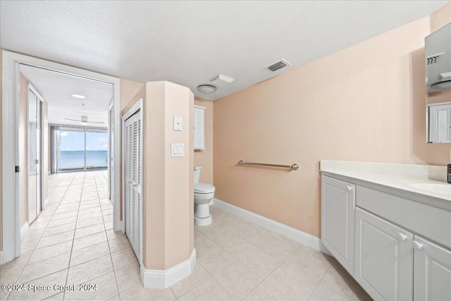 bathroom with a textured ceiling, toilet, vanity, visible vents, and baseboards