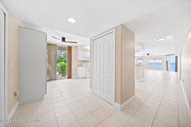 hall featuring light tile patterned floors and baseboards