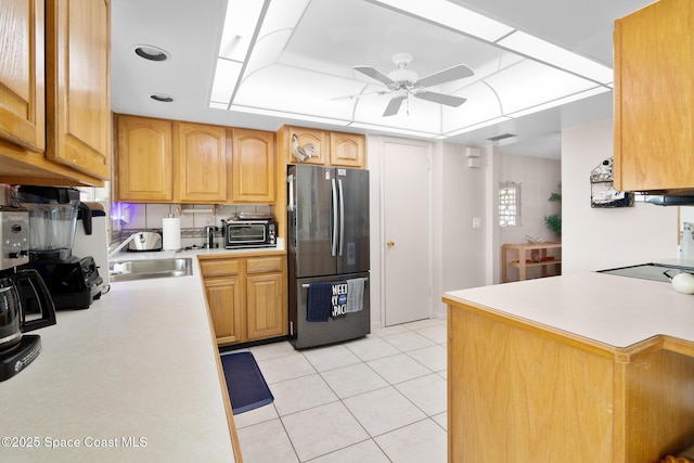kitchen featuring light tile patterned floors, a sink, light countertops, freestanding refrigerator, and a raised ceiling