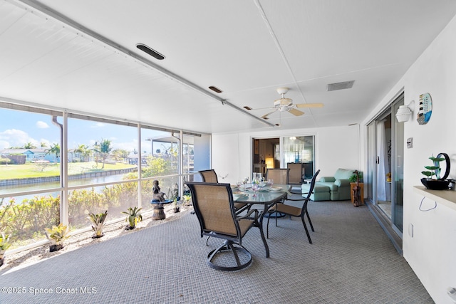 sunroom with a water view, ceiling fan, and visible vents