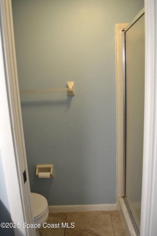 bathroom featuring a stall shower, baseboards, toilet, and tile patterned floors