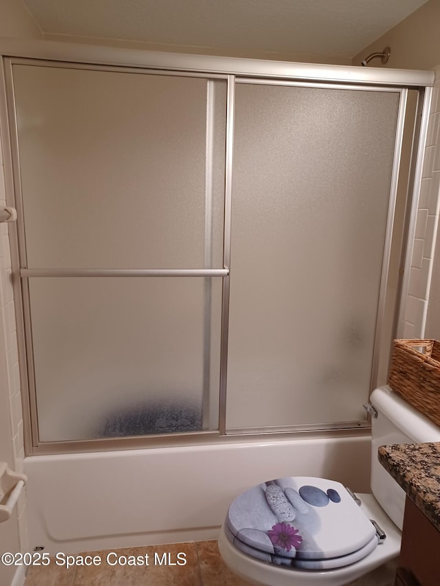 bathroom with toilet, shower / bath combination with glass door, tile patterned flooring, and vanity