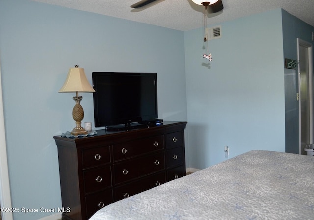 bedroom featuring a ceiling fan, visible vents, and a textured ceiling