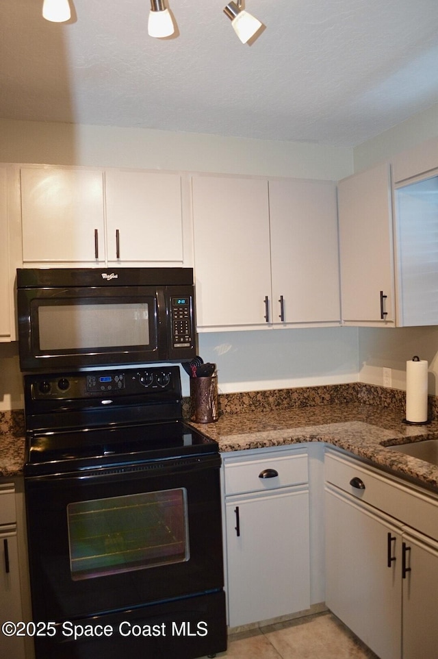 kitchen featuring dark stone counters, white cabinets, a sink, and black appliances