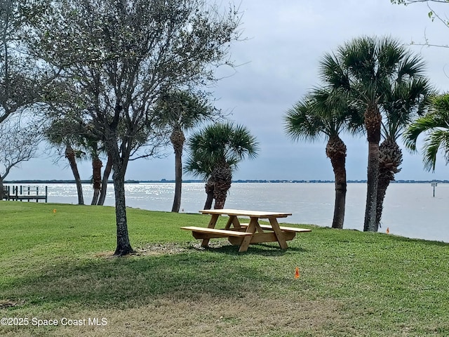 view of home's community with a water view and a lawn