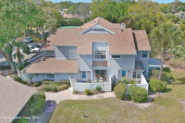 exterior space featuring roof with shingles, a chimney, and a front lawn