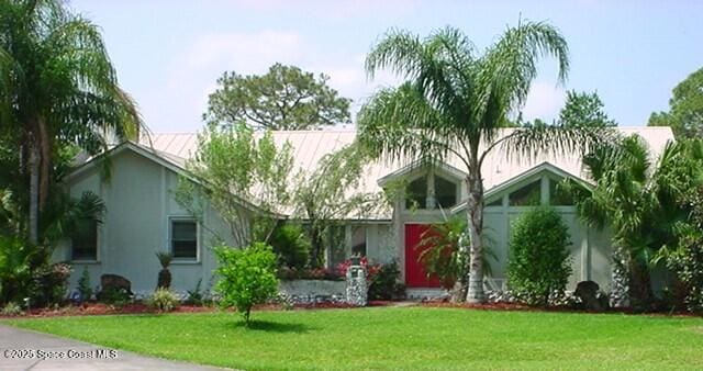 view of front of property with stucco siding, metal roof, and a front yard