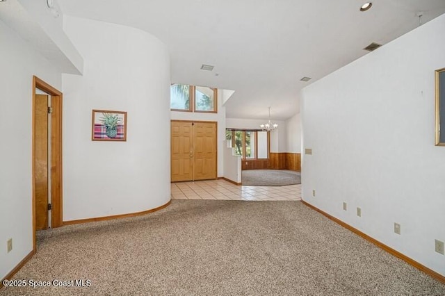 foyer entrance featuring visible vents, carpet, tile patterned flooring, lofted ceiling, and a chandelier