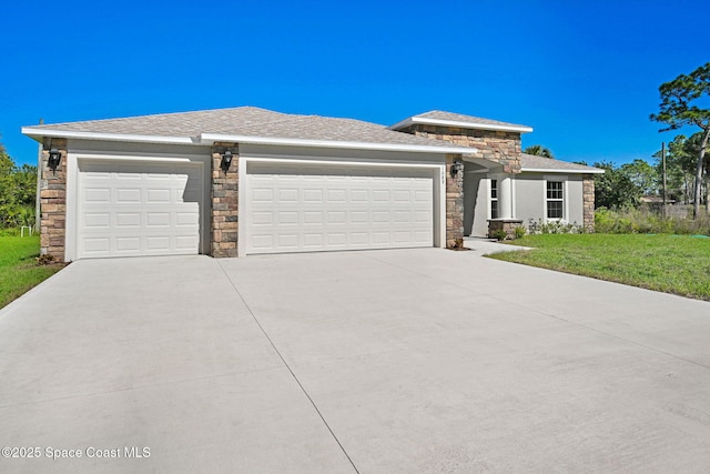 prairie-style home featuring a garage, stone siding, a front lawn, and driveway