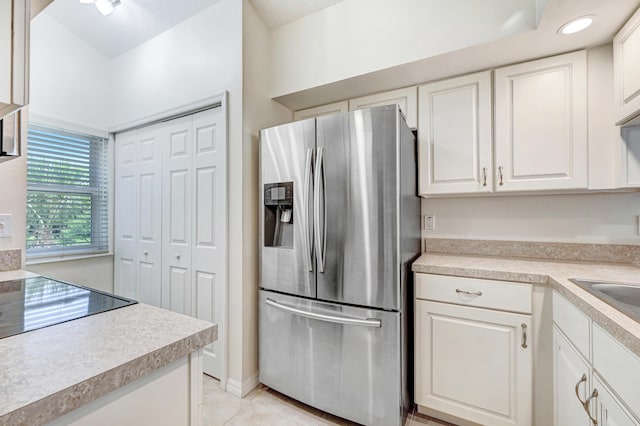 kitchen featuring stainless steel refrigerator with ice dispenser, light tile patterned floors, recessed lighting, light countertops, and white cabinetry