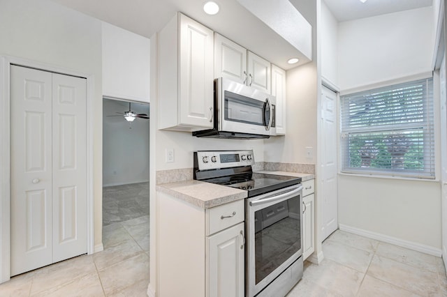 kitchen featuring light tile patterned floors, stainless steel appliances, baseboards, white cabinets, and light countertops