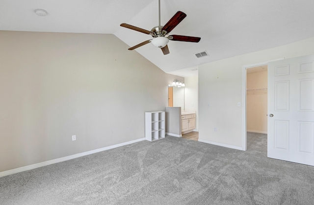 unfurnished bedroom with lofted ceiling, light colored carpet, visible vents, a spacious closet, and baseboards