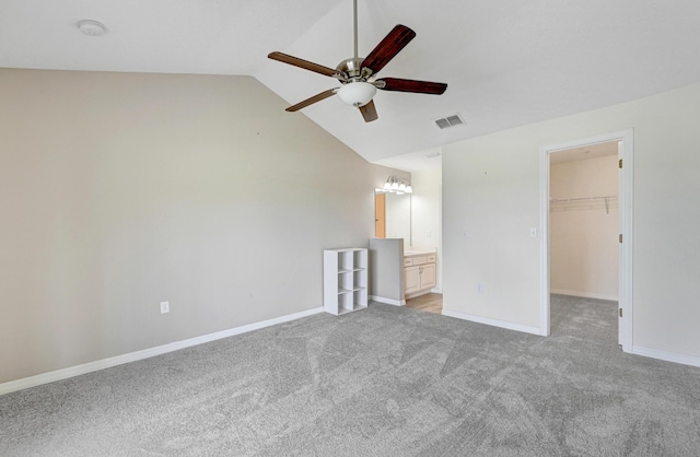 unfurnished bedroom featuring lofted ceiling, light colored carpet, visible vents, a spacious closet, and baseboards