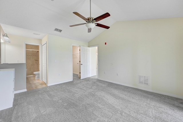 unfurnished bedroom featuring carpet, visible vents, lofted ceiling, and ensuite bathroom