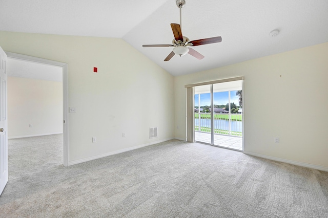 carpeted empty room featuring lofted ceiling, ceiling fan, visible vents, and baseboards