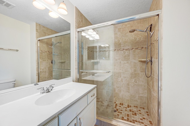 bathroom featuring a stall shower, visible vents, a textured ceiling, and vanity