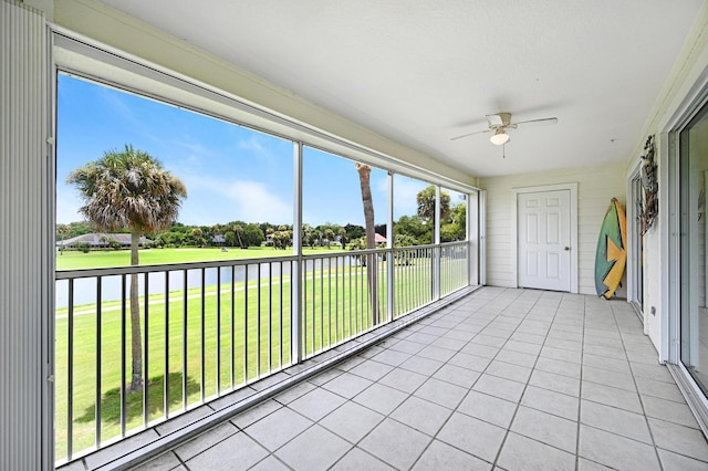 unfurnished sunroom with a water view and ceiling fan