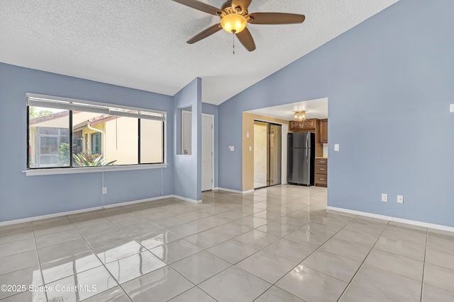 empty room with lofted ceiling, light tile patterned floors, a textured ceiling, and baseboards