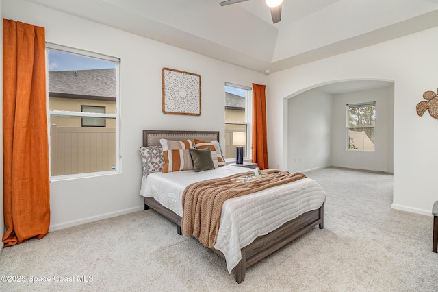 carpeted bedroom with arched walkways, ceiling fan, and baseboards